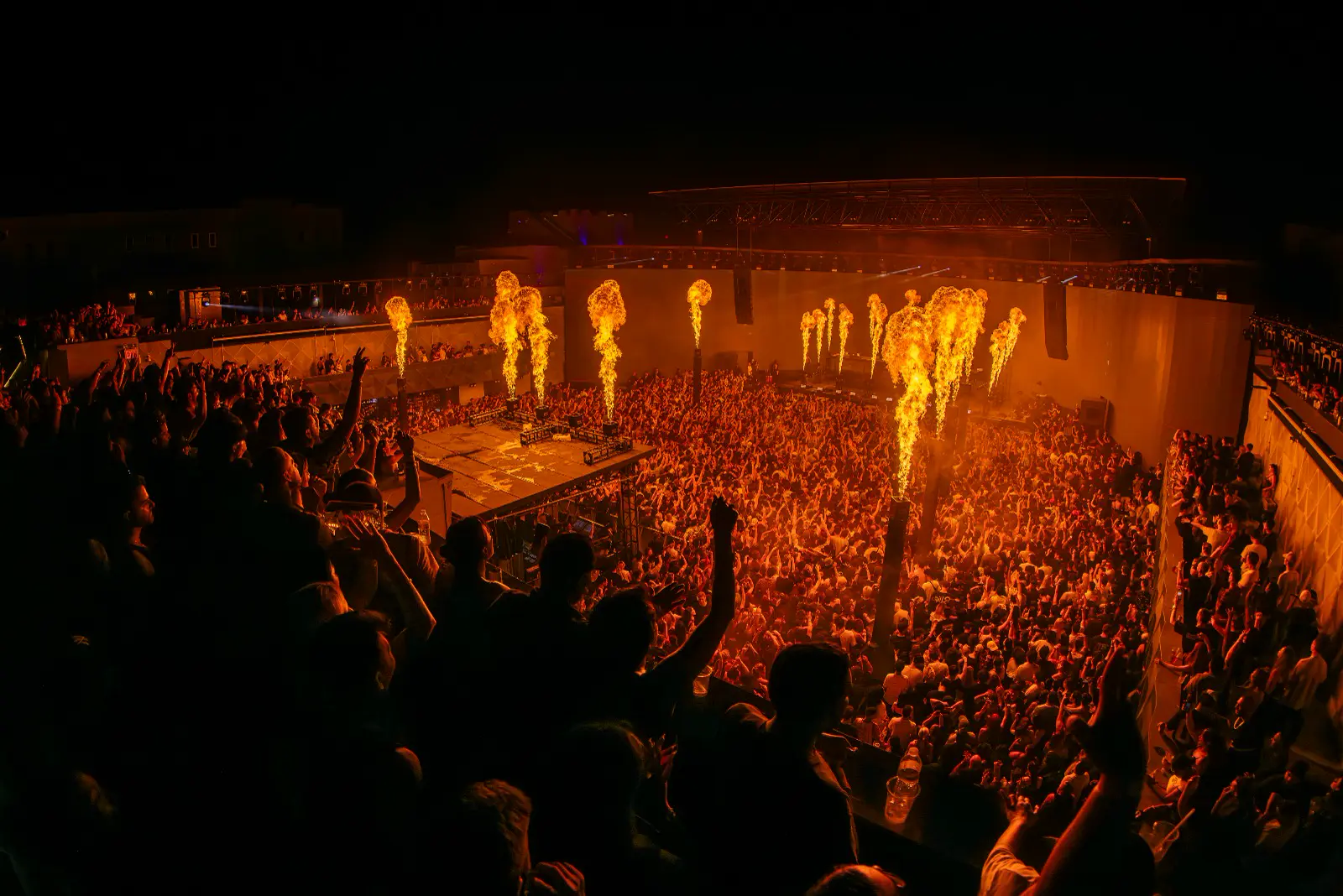Flame effects rising over a crowd in an open-air venue